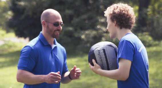 Trainer doing a medicine ball work out with a young man