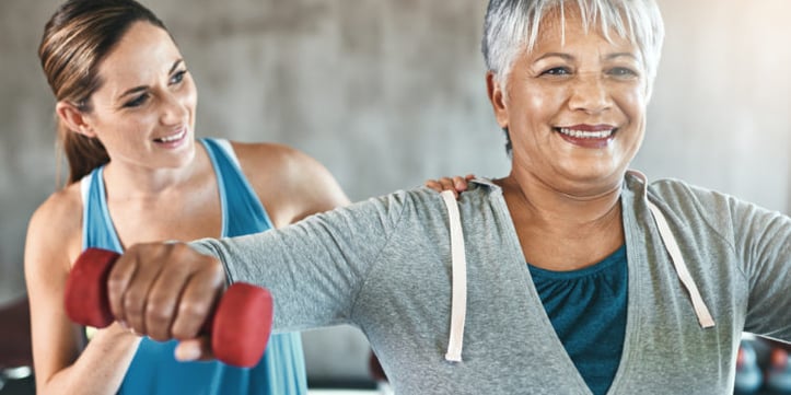 A female trainer helping an older woman with a exercise