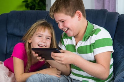 Boy and girl looking at tablet and laughing