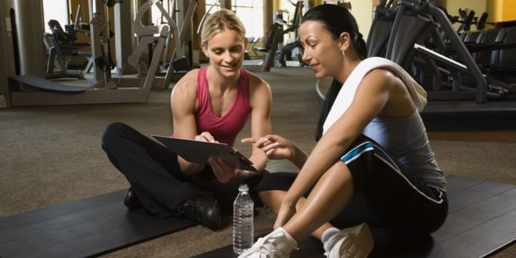Trainer sitting down with a client showing her clip board
