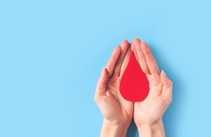Hands holding blood drop in hands