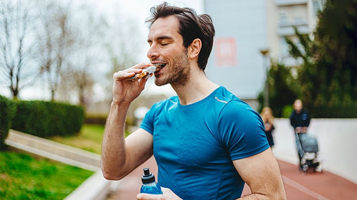 Man eating granola bar outside