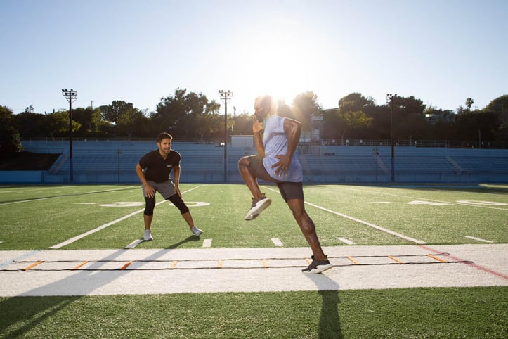 NASM trainer assisting athlete with drill on outside track