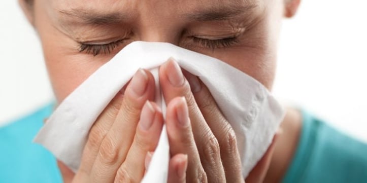 Someone blowing nose with tissue