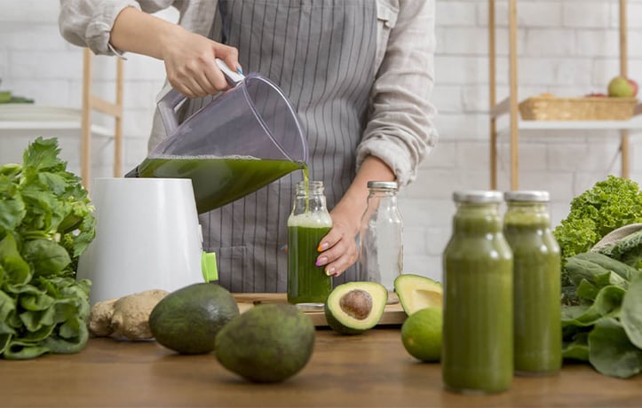 Person making green juice in kitchen