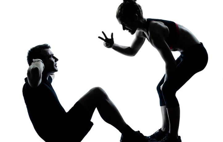 Trainer helping client with sit ups