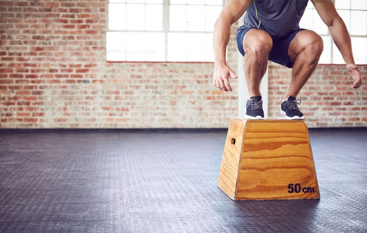 Male performing box jump on wood box