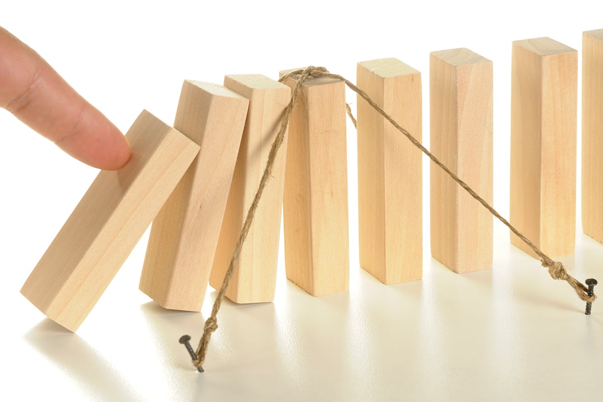 a person pushing over a row of dominos