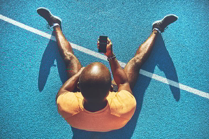 trainer sitting on ground looking at phone