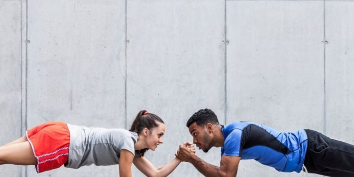 female and male doing a plank and cross holding hands