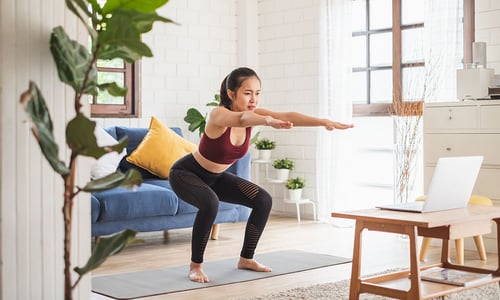 a woman doing a body weight squat in her home