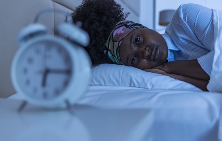 A woman laying down looking at a clock