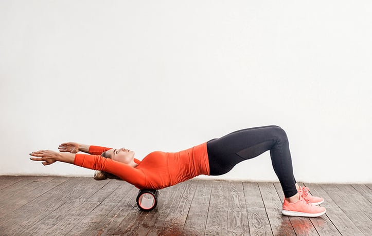 woman using foam roller on upper back area
