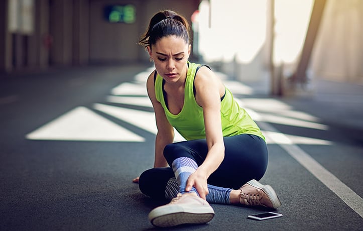 Woman holding at her ankle looks in pain