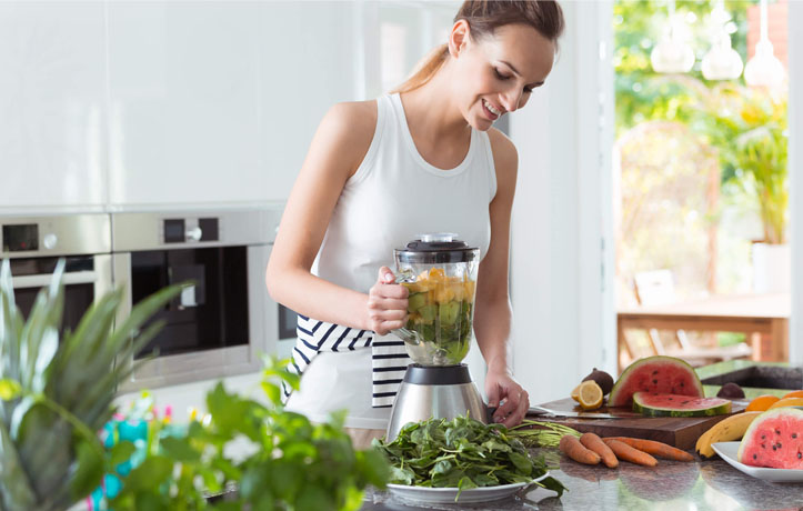 a woman blending vegetables in the kitchen