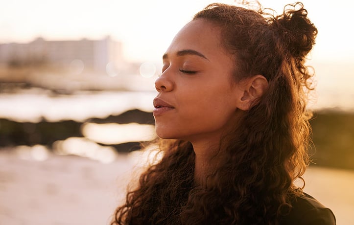 a woman lowering her cortisol through deep breathing and relaxation