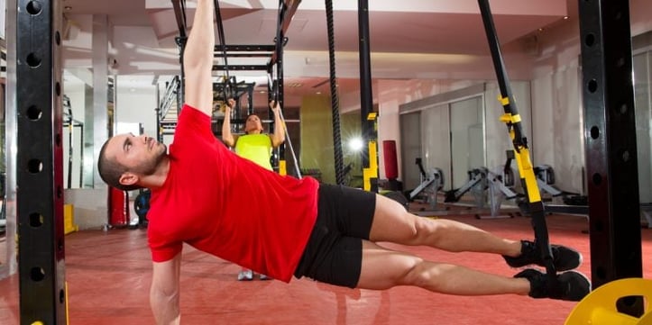 trainer doing suspended hamstring stretches