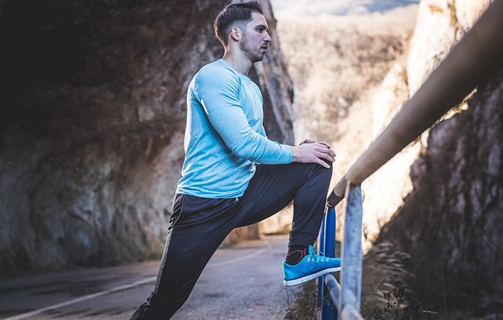 man performing it band stretches against a railing