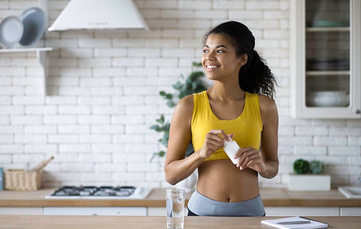 a woman taking l-arginine supplements in a kitchen