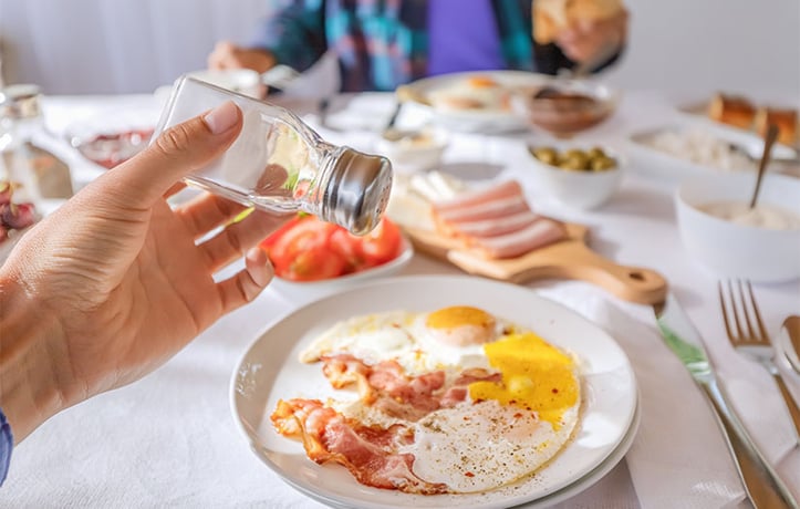 someone adding salt to a plate of eggs