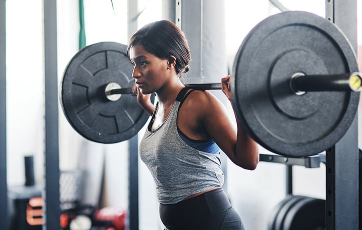 woman doing back squats with barbell and plates