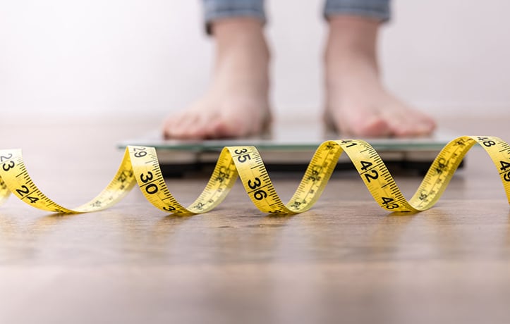 a woman on a scale measuring if she's skinny fat