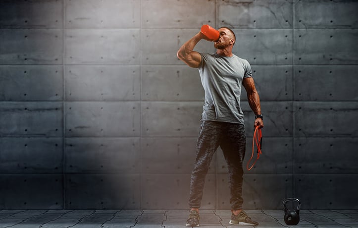 male drinking out of shaker bottle with jump rope in hand