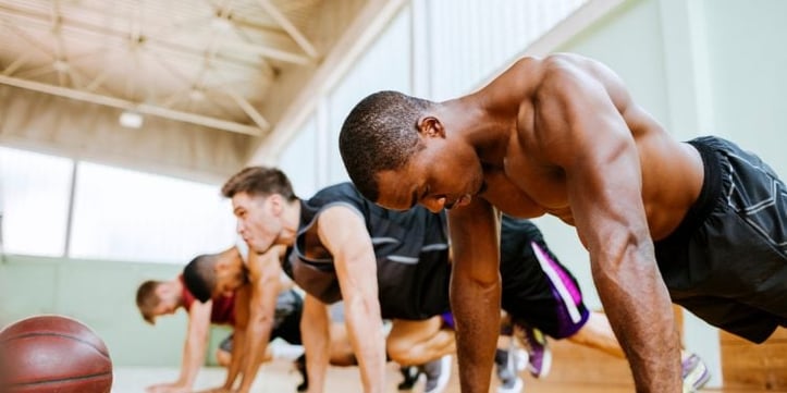 Athletes doing plans inside basketball gym