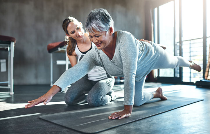 A wellness coach helping an elderly lady stretch