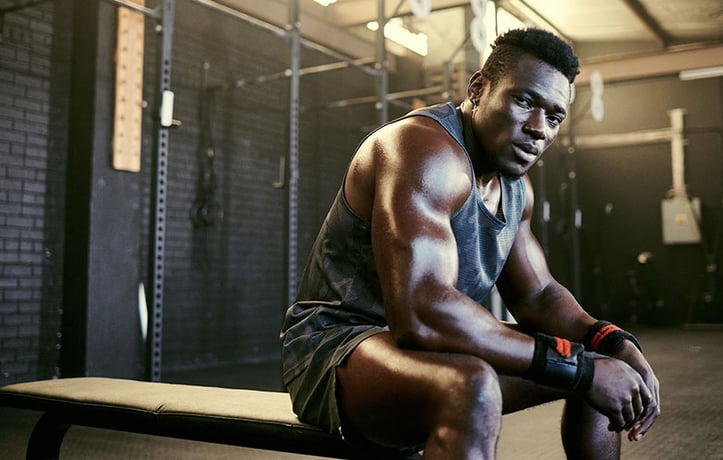 a bodybuilder sitting on a bench in a gym
