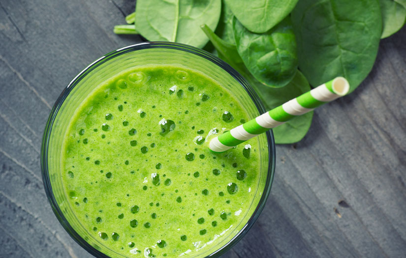Green smoothie with spinach in background