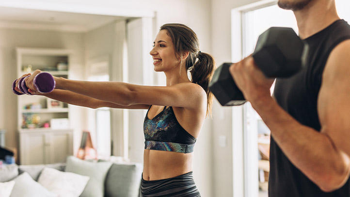 Woman doing lateral raises with dumbbells at home