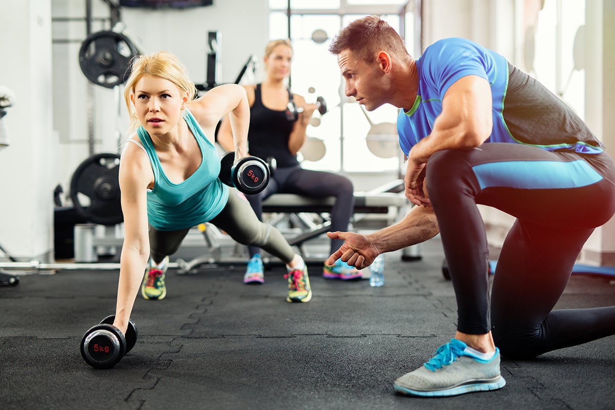 Client doing bent-over rows next to trainer