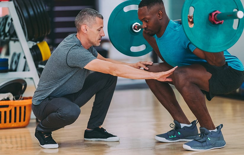 trainer showing client how to perform a squat