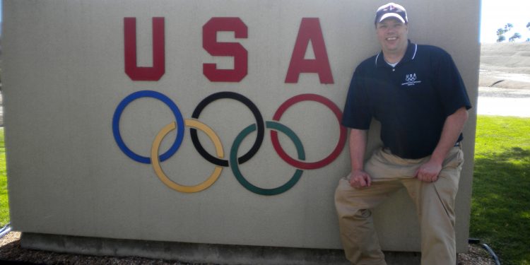 Craig Couillard standing in front of USA Olympics wall