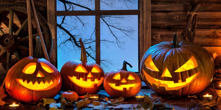 Carved halloween pumpkins sitting next to window seal
