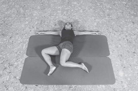 woman lying on back doing a dynamic stretch on mat