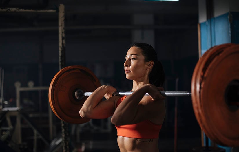 woman doing a front squat with a barbell and plates