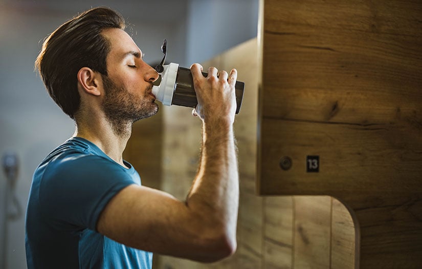 man drinking pre-workout from a shaker bottle