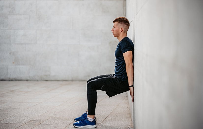 a man doing wall sits outside