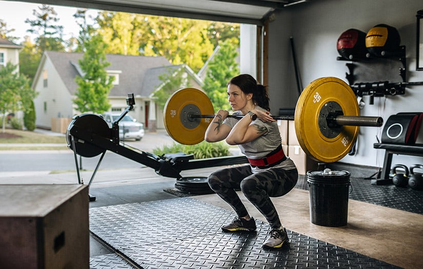 Female personal trainer helping a young man lift dumbells while